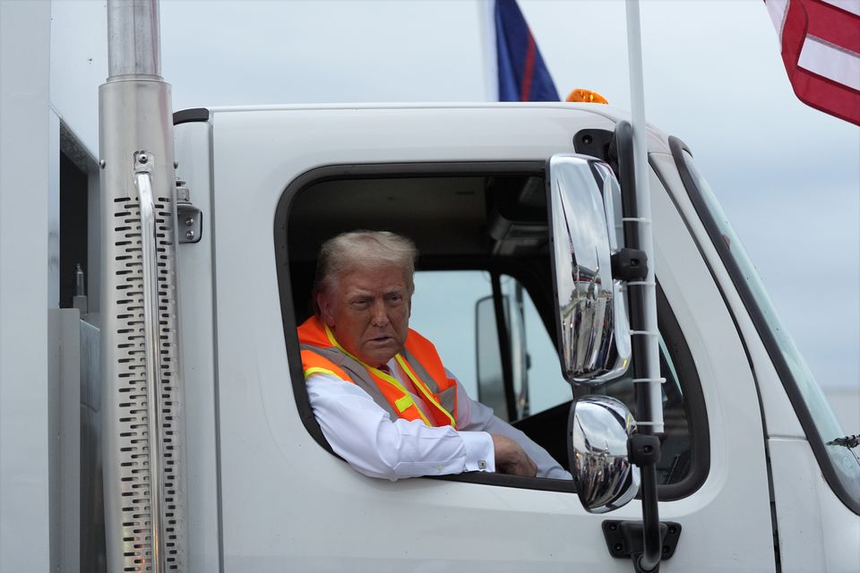 Donald Trump talks to reporters as he sits in a garbage truck (Julia Demaree Nikhinson/AP)