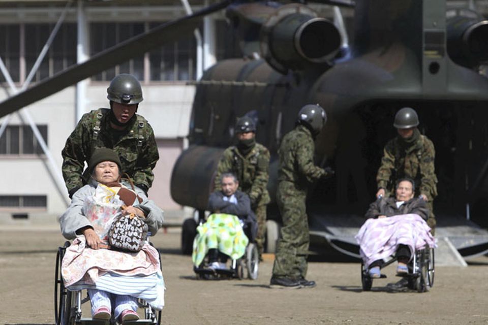 ALTERNATE CROP OF TOK890 OF MARCH 13, 2011 - Futaba Kosei Hospital patients are assisted by Japan Self Defense Force personnel as they disembark from a helicopter in the compound of Fukushima Gender Equality Centre in Nihonmatsu, Fukushima Prefecture, northeastern Japan, Sunday morning, March 13, 2011 after being evacuated from the hospital in Futaba town near the troubled Fukushima Dai-ichi nuclear complex. They might have been exposed to radiation while waiting for evacuation when an explosion of Unit 1 reactor of the complex blew off the top part of its walls on Saturday, one day after a strong earthquake and tsunami hit northeastern Japan. (AP Photo/The Yomiuri Shimbun, Daisuke Tomita)  JAPAN OUT, CREDIT MANDATORY