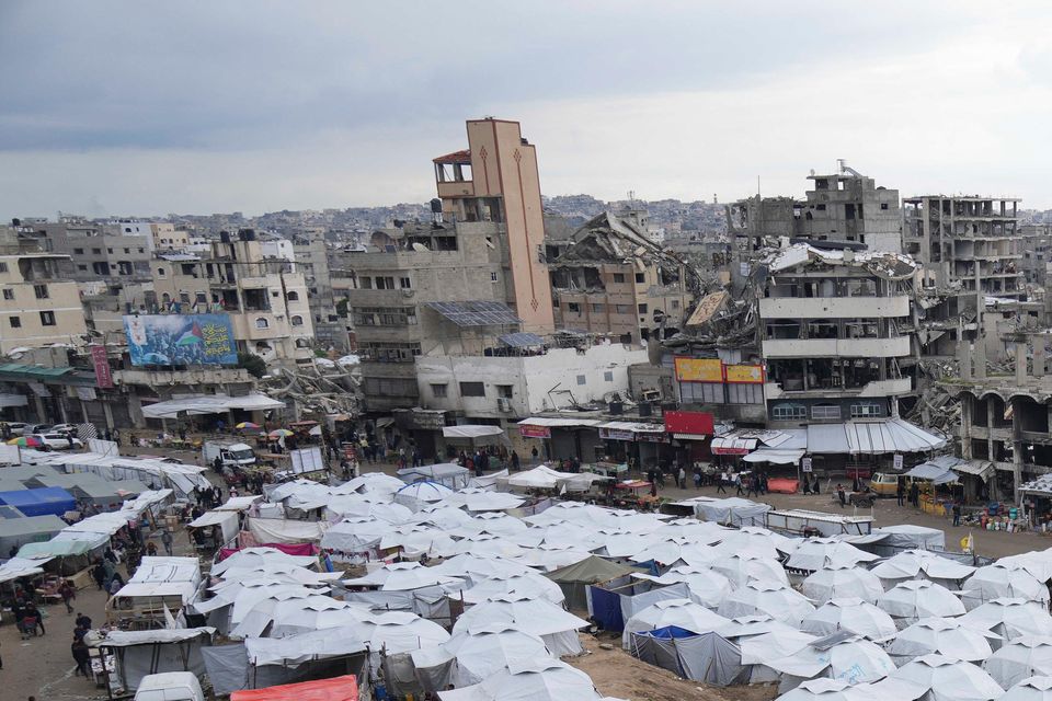 A sprawling tent camp for displaced Palestinians sits adjacent to destroyed homes and buildings in Gaza City (Abdel Kareem Hana/AP)