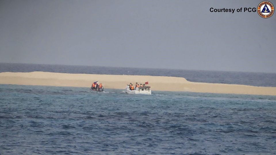 Chinese Coast Guard boat sails near Sandy Cay, seen in the background, in the South China Sea (Philippine Coast Guard via AP)