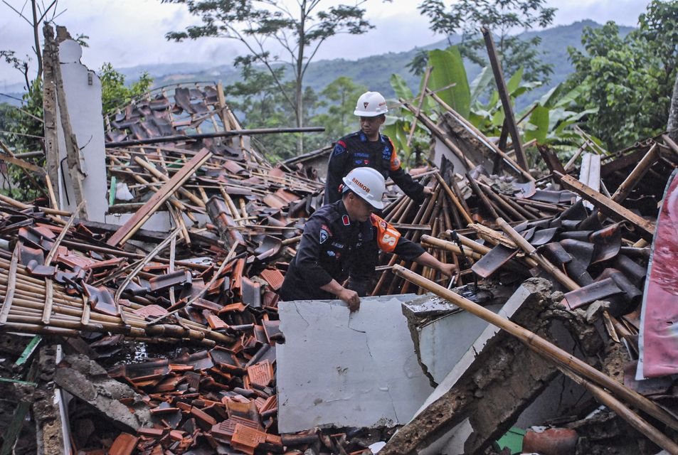 Rescuers clear up rubble from damaged houses at a neighbourhood affected by a landslide in Sukabumi, West Java, Indonesia (Rangga Firmansyah/AP)