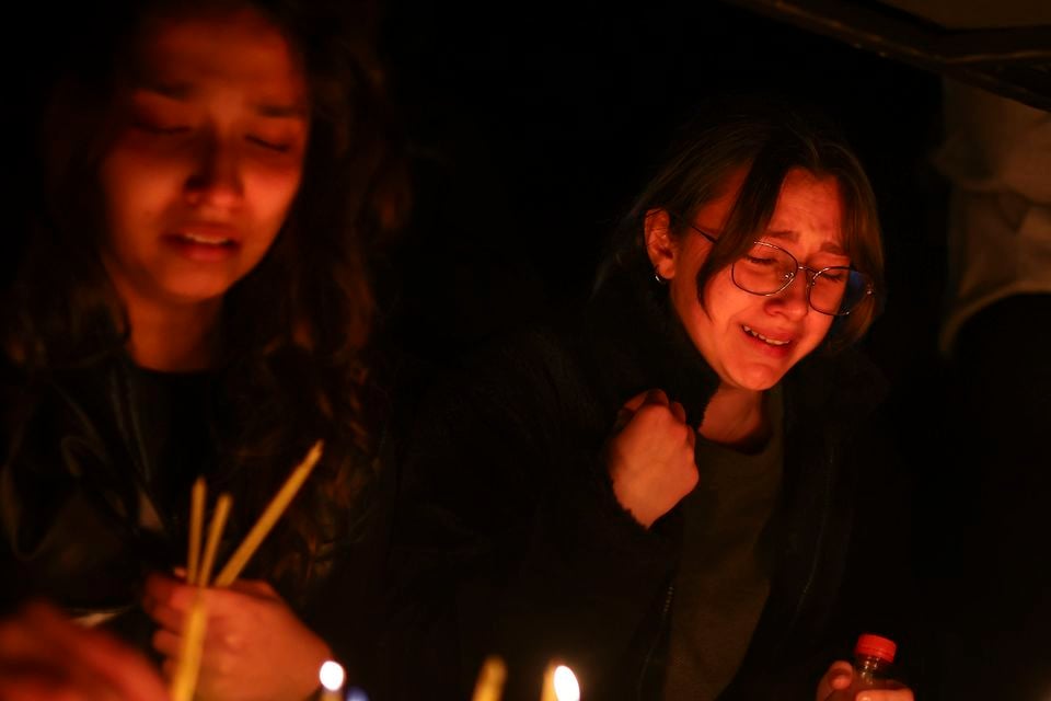 Girls cry as they light candles in the town of Kocani (Armin Durgut/AP)