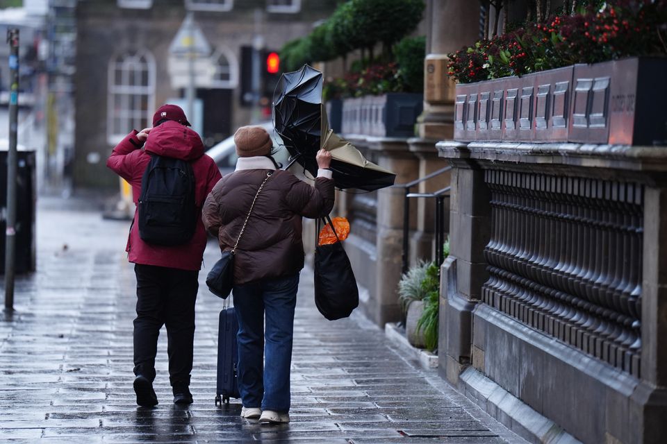 A couple battle with an umbrella in the wind during Storm Eowyn on Princes Street, Edinburgh (Jane Barlow/PA)