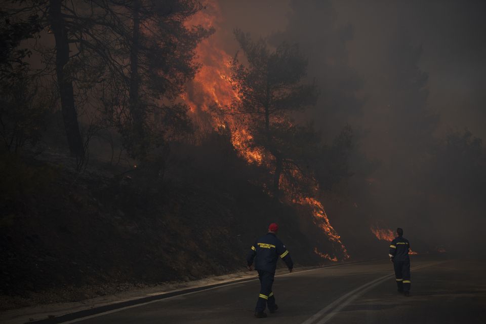 Firefighters inspect flames near a road in Varnava village (Michael Varaklas/AP)