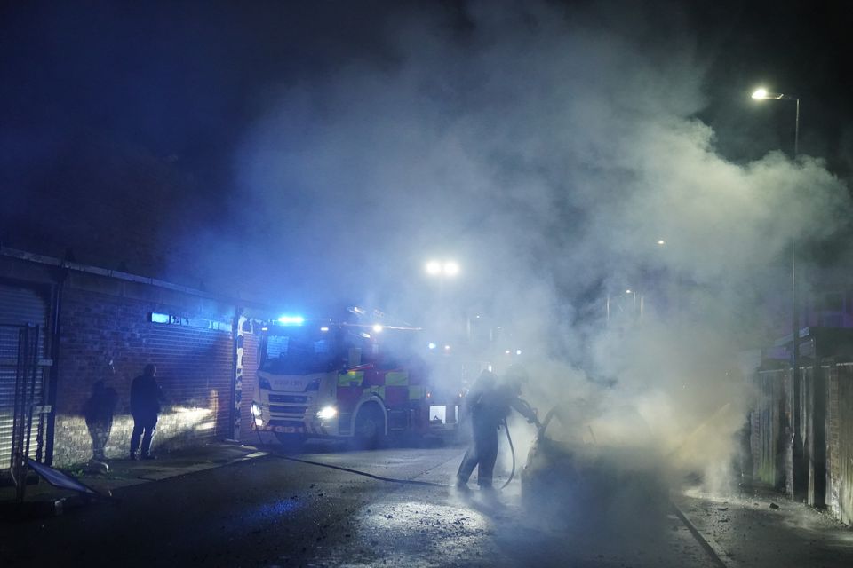 Firefighters tend to a burning police car burns as officers are deployed on the streets of Hartlepool following a violent protest (Owen Humphreys/PA)