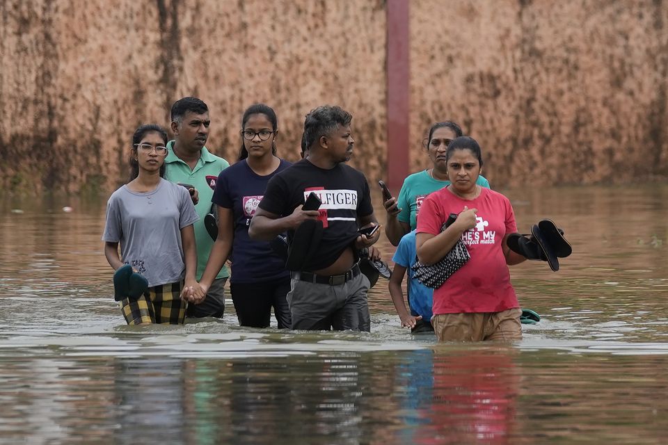 People wade through a submerged street in Colombo, Sri Lanka (Eranga Jayawardena/AP)