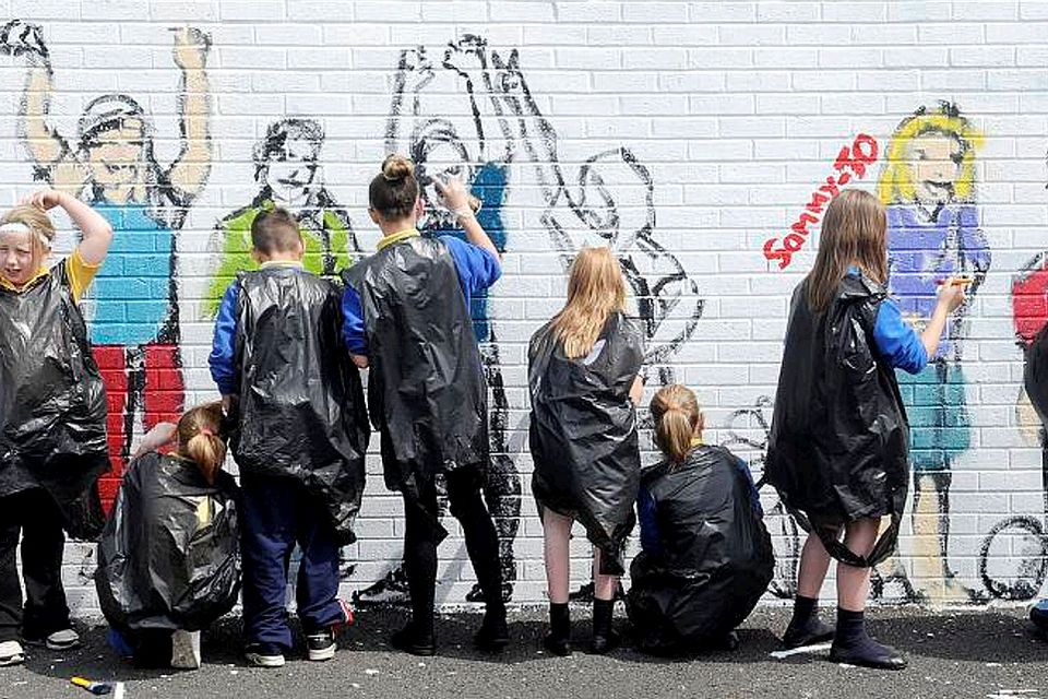 Children from a local school painting a new mural in the lower Shankill area