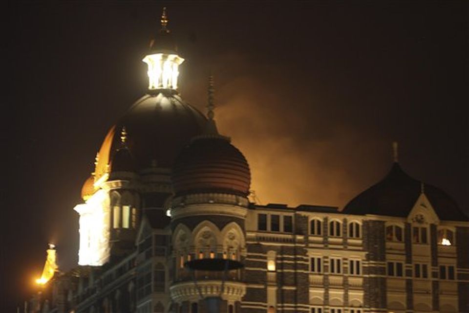 Smoke emerges from behind a dome on the Taj Hotel in Mumbai, India, Wednesday, Nov. 26, 2008. Teams of heavily armed gunmen stormed luxury hotels, a popular tourist attraction and a crowded train station in at least seven attacks in India's financial capital, killing at least 78 people and wounding at least 200, officials said. The gunmen were specifically targeting Britons and Americans, media reports said, and may be holding hostages. The gunmen also attacked police headquarters in south Mumbai, the area where most of the attacks, which began late Wednesday and continued into Thursday morning, took place.  (AP Photo/Gautam Singh)