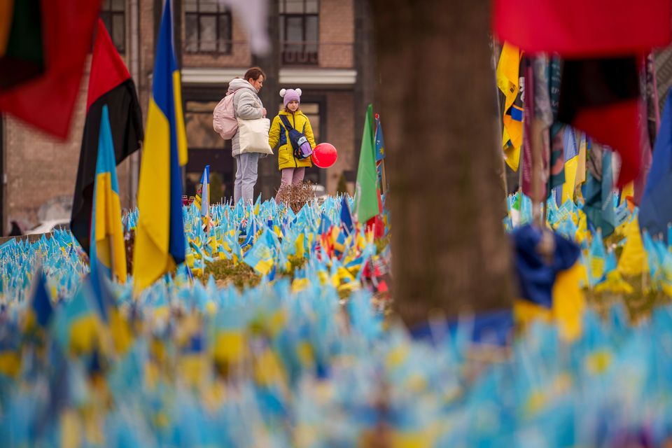 A child holds a balloon while looking at a memorial for soldiers killed in the war (Vadim Ghirda/AP)