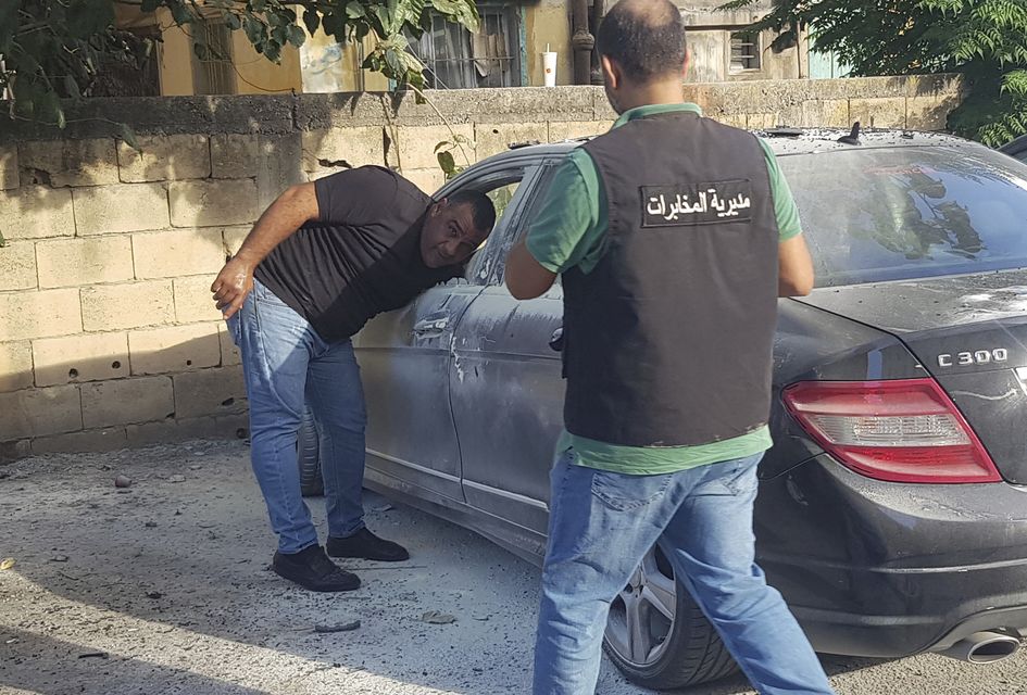 Lebanese security officers check a partly damaged car after what is believed to be the result of a walkie-talkie exploding inside it, in the southern port city of Sidon (Mohammed Zaatari/AP)