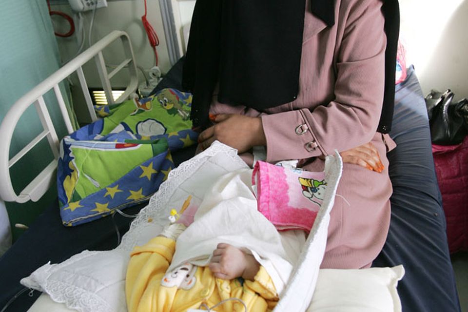 An Iraqi woman sits with her sick child on November 12, 2009 at Falluja General Hospital in the city of Falluja west of Baghdad, Iraq