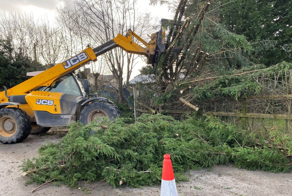 A farmer moves a fallen tree on a farm path in Bramhall, Cheshire (Abigail Kemp/PA)