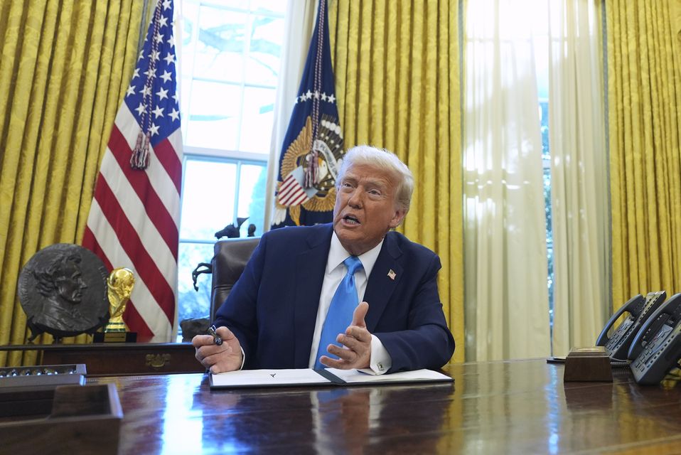 Donald Trump speaks to reporters as he signs executive orders in the White House (Evan Vucci/AP)