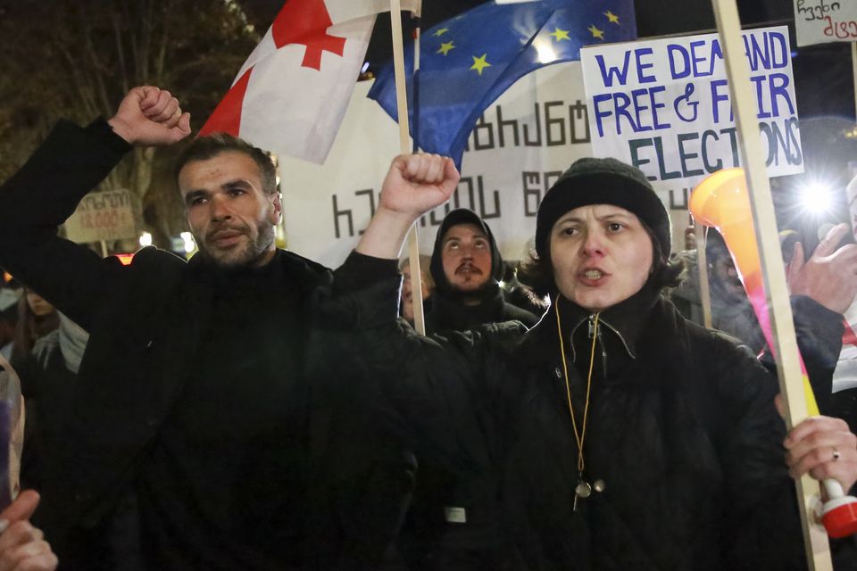 Demonstrators with a Georgian national flag and an EU flag rally outside the parliament to protest against the government’s decision to suspend negotiations on joining the European Union in Tbilisi (Zurab Tsertsvadze/AP)