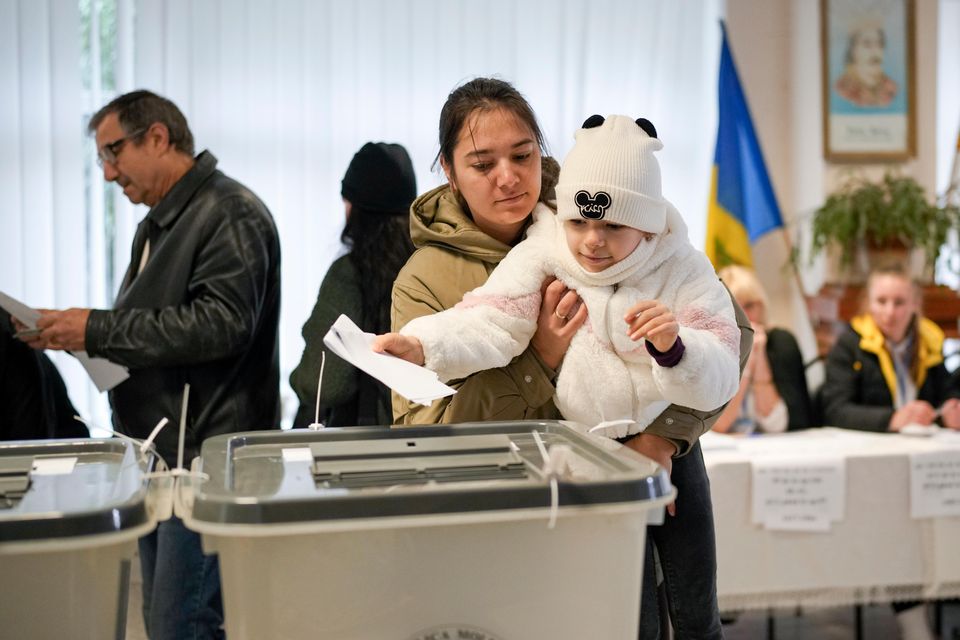 A woman holds a child as she casts her vote in Chisinau, Moldova (Vadim Ghirda/AP)