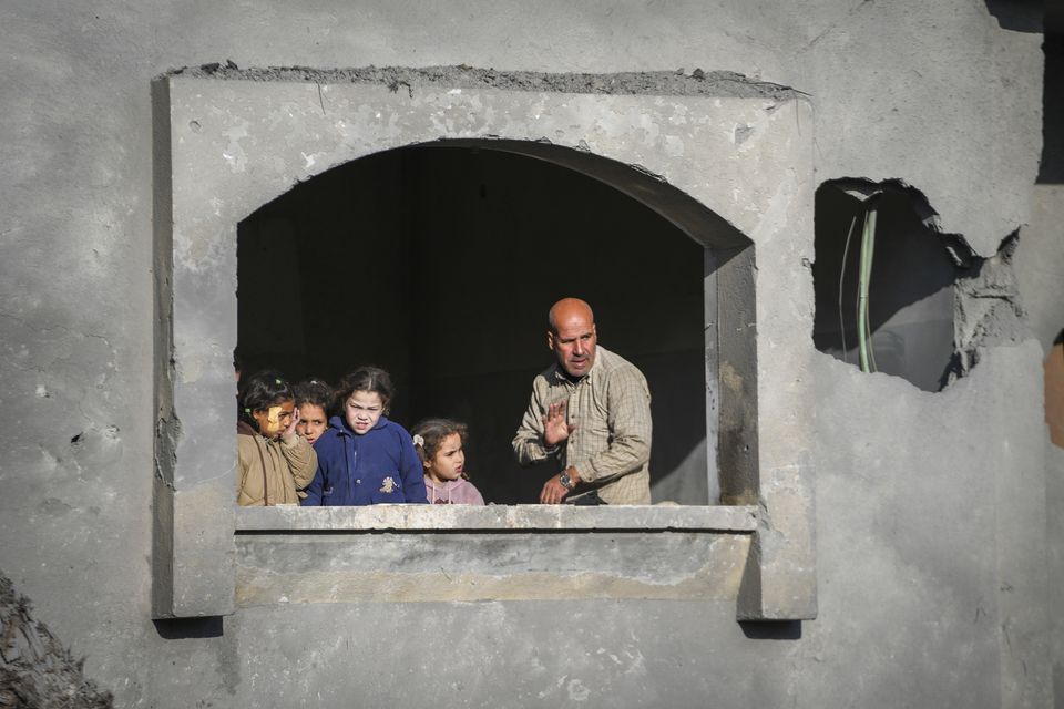 Neighbours watch the funeral procession of the victims of an Israeli air strike on a home in Deir al-Balah, central Gaza Strip (AP Photo/Abdel Kareem Hana)