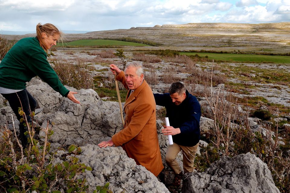 THE BURREN, IRELAND - MAY 19:  Prince Charles, Prince of Wales is helped up a short climb by Brigid Barry and Brendan Dunford during his visit to The Burren, an ancient and dramatic stony outcrop famed for its rare plant life, biodiversity and archaeology, on the first day of his Royal visit to the Republic of Ireland on May 19, 2015 in County Clare, Ireland. The Prince of Wales and Duchess of Cornwall arrived in Ireland today for their four day visit to the Republic and Northern Ireland, the visit has been described by the British Embassy as another important step in promoting peace and reconciliation. (Photo by John Stillwell - WPA Pool/Getty Images)