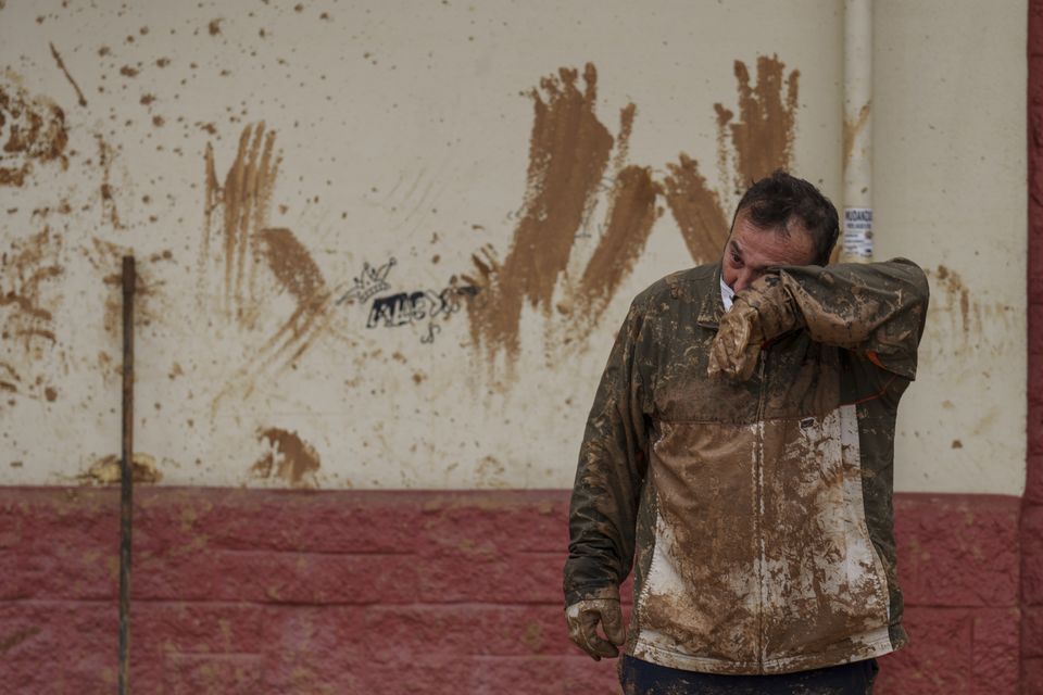 A man wipes mud off his face in an area affected by floods in Catarroja, Spain (Manu Fernandez/AP)