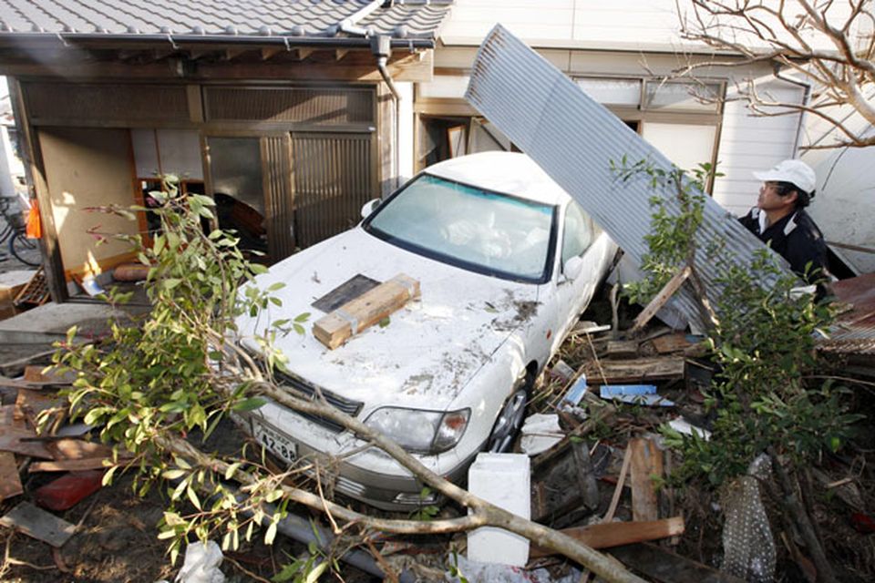 A resident of the seaside town of Yotsukura, northern Japan, clears debris from his home Monday, March 14, 2011, three days after a giant quake and tsunami struck the country's northeastern coast. (AP Photo/Mark Baker)