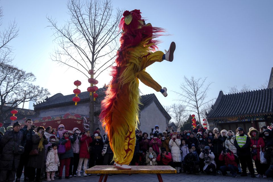 People watch an artiste perform an acrobatic lion dance at the Dongyue Temple in Beijing on the first day of the Chinese Lunar New Year (Andy Wong/AP)