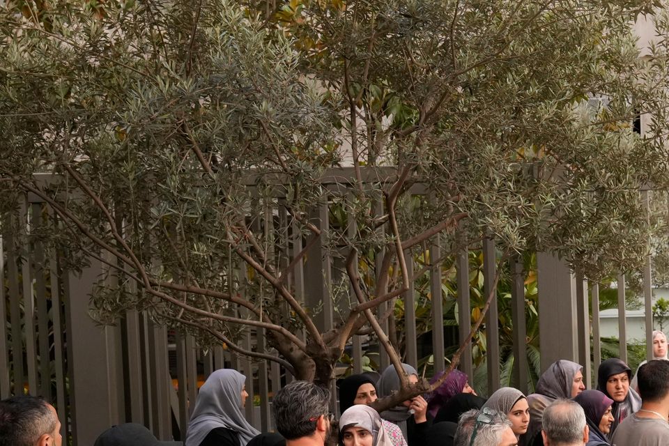 People wait outside the hospital as an ambulance brings in a casualty wounded by an exploding pager on Tuesday (AP Photo/Hussein Malla)