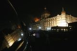 thumbnail: Smoke and flames rising from one of the wings of the Taj Palace Hotel, are also reflected in car window, in Mumbai, India, Thursday, Nov. 27, 2008.  Indian commandoes killed the last three gunman at a landmark hotel late Thursday and were sweeping another luxury hotel in search of hostages and trapped people after suspected Muslim militants stormed targets across Mumbai, leaving at least 119 people dead. (AP Photo/Gautam Singh)