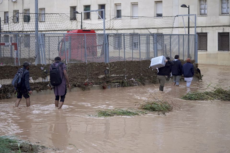 People walk through flooded streets in Valencia (Alberto Saiz/AP)