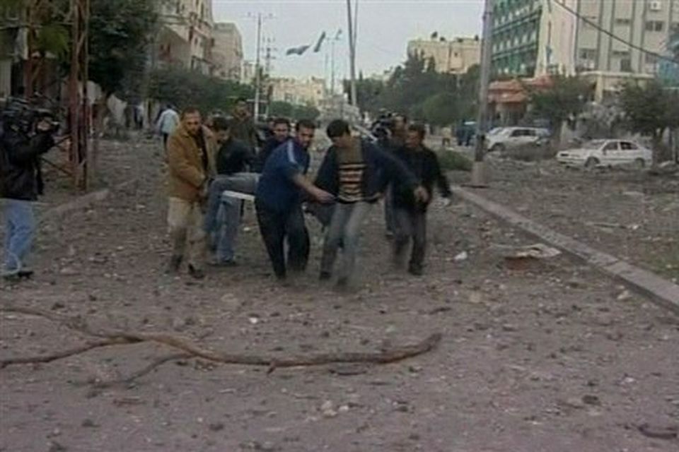 In this image taken from APTN video young men carry a badly injured man on a stretcher to an awaiting vehicle as debris lies in the road after Israeli aircraft struck Hamas security compounds across Gaza in Gaza City on Saturday Dec. 27, 2008. Hamas and medics reported that dozens of people were killed and that others were still buried under the rubble. The strikes caused widespread panic and confusion, as black clouds of smoke rose above Gaza. (AP Photo/APTN)