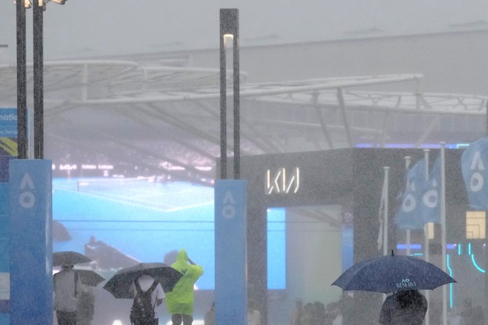 Spectators try to shelter from heavy rain at Melbourne Park (Manish Swarup/AP)