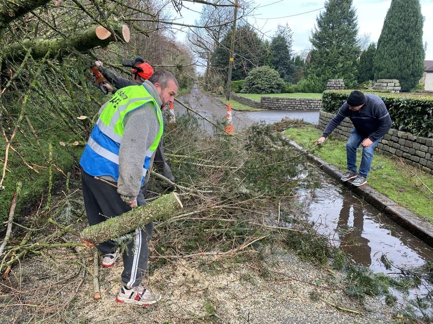 Local residents removing the trees which blocked the road (Jonathan McCambridge/PA)