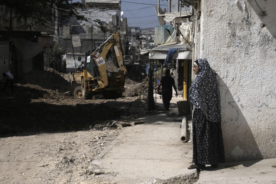 A Palestinian woman watches an operation by the Israeli military in Tulkarem refugee camp in the West Bank (Majdi Mohammed/AP)