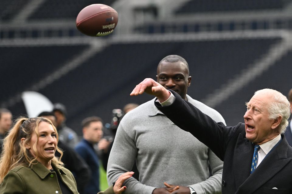 The King was taught how to throw an American football during a visit to Tottenham Hotspur Stadium on Wednesday (Eddie Mulholland/Daily Telegraph/PA)