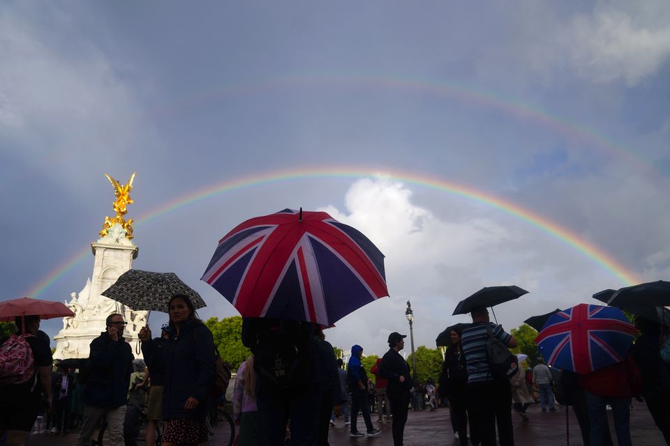 A double rainbow is seen, as members of the public gather outside Buckingham Palace (Victoria Jones/PA)