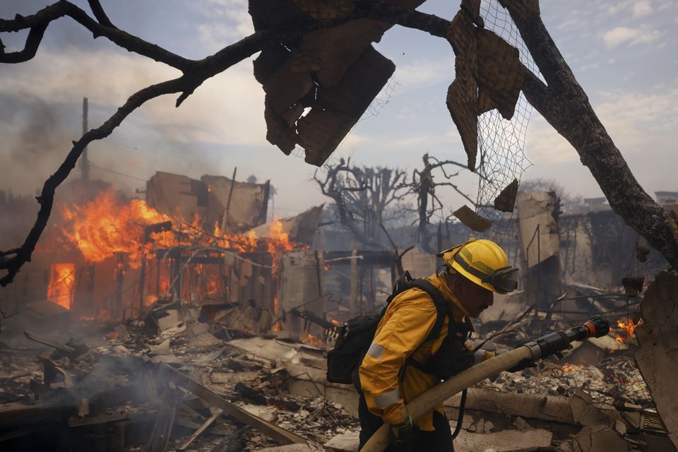 A firefighter battles the Palisades Fire around a burned structure in the Pacific Palisades neighbourhood of Los Angeles  (AP/Etienne Laurent)