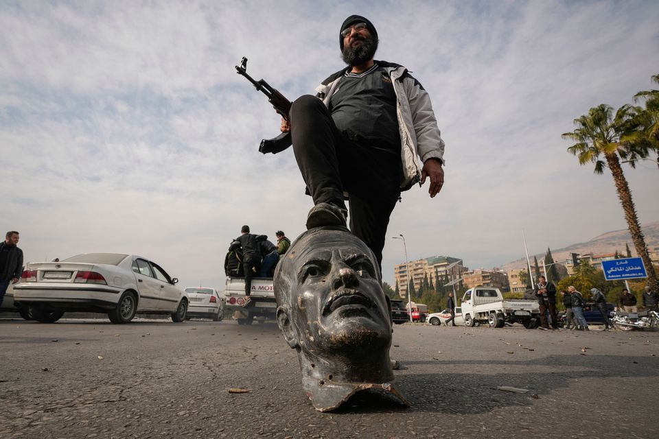 An opposition fighter steps on a broken bust of the late Syrian president Hafez Assad in Damascus (AP Photo/Hussein Malla)