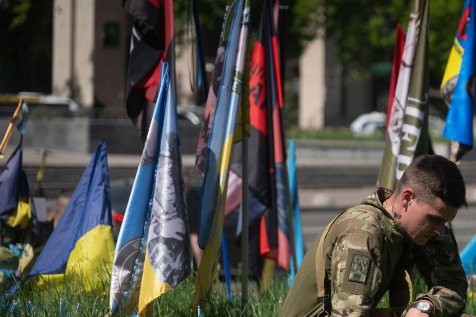 A Ukrainian soldier plants a small national flag on a grassed area in Independence Square (Efrem Lukatsky/AP)