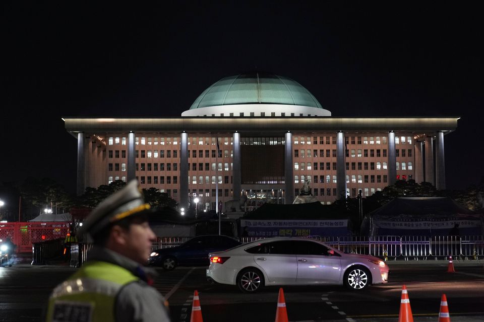 A traffic police officer walks near the National Assembly as a rally demanding South Korean President Yoon Suk Yeol’s impeachment is taking place, in Seoul (Lee Jin-man/AP)