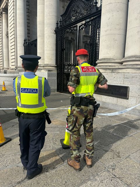 A Garda officer and a military police officer look at damage caused to gates outside Government Buildings in Merrion Street, Dublin (Cate McCurry/PA)