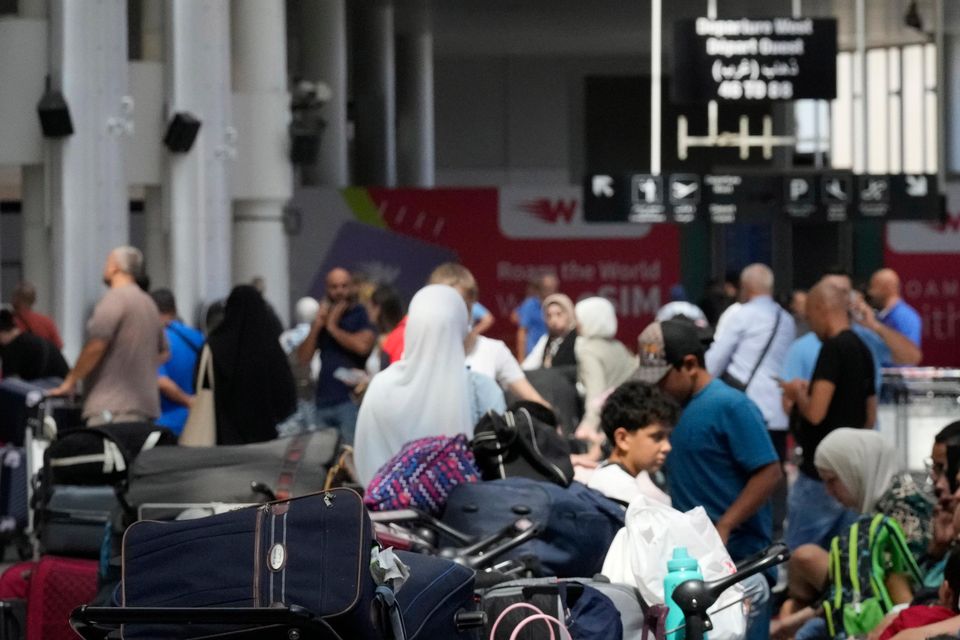 Passengers whose flights were cancelled wait at the departure terminal of Rafik Hariri International Airport in Beirut (Hussein Malla/AP)