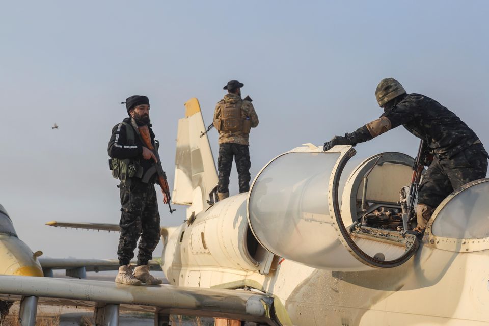 Syrian opposition fighters stand on an aircraft at the Al-Nayrab military airport after taking control of the facility on the outskirts of Aleppo (Omar Albam/AP)