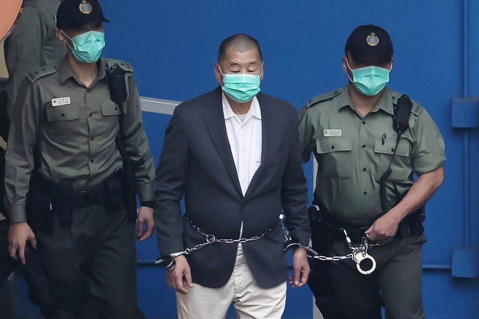 Jimmy Lai, centre, who founded the Apple Daily tabloid, is escorted by Correctional Services officers to get on a prison van (AP Photo/Kin Cheung)