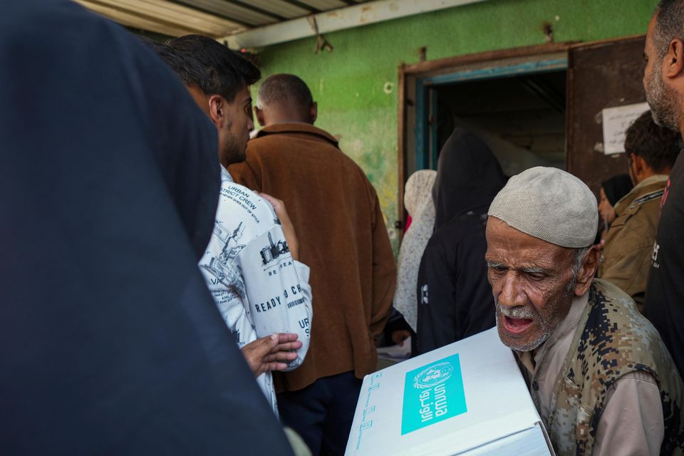 Palestinians receive aid distributed by UNRWA (Abdel Kareem Hana/AP)