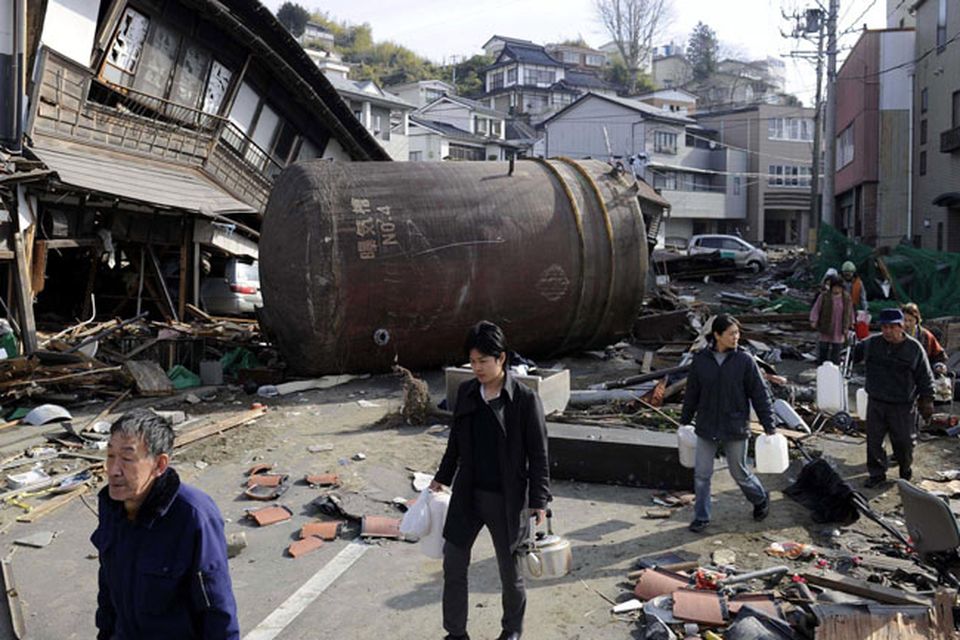 People walk to receive water supply through a street with the rubble Monday March 14, 2011 in Kesennuma, Miyagi Prefecture, northern Japan  following Friday's massive earthquake and the ensuing tsunami. (AP Photo/Kyodo News) JAPAN OUT, MANDATORY CREDIT, NO SALES IN CHINA, HONG  KONG, JAPAN, SOUTH KOREA AND FRANCE