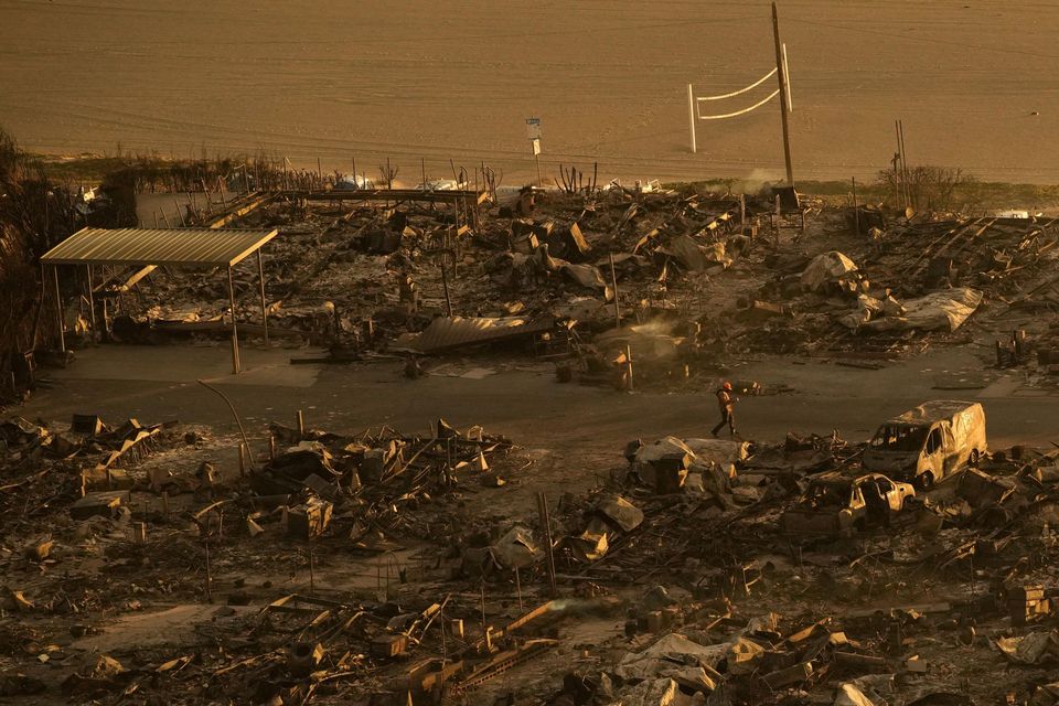 A person walks through a neighbourhood destroyed by the Palisades Fire (John Locher/AP)