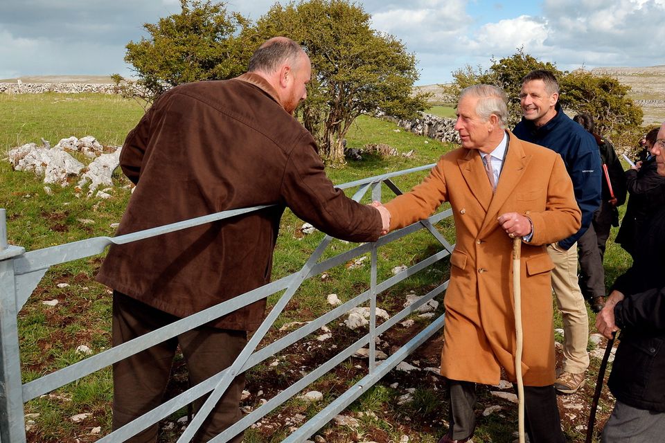 THE BURREN, IRELAND - MAY 19:  Prince Charles, Prince of Wales shakes hands with local farmer Oliver Nagle with his father Pat (R) looking on during his visit to The Burren, an ancient and dramatic stony outcrop famed for its rare plant life, biodiversity and archaeology, on the first day of his Royal visit to the Republic of Ireland on May 19, 2015 in County Clare, Ireland. The Prince of Wales and Duchess of Cornwall arrived in Ireland today for their four day visit to the Republic and Northern Ireland, the visit has been described by the British Embassy as another important step in promoting peace and reconciliation. (Photo by John Stillwell - WPA Pool/Getty Images)