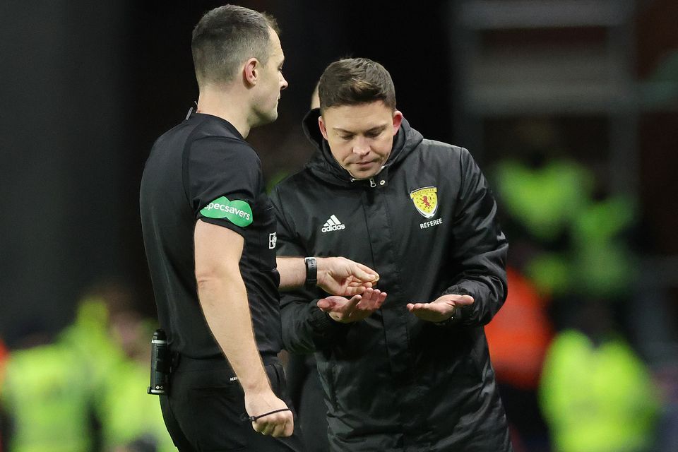 Referee Don Robertson (left) passes an object that was thrown from the crowd towards Celtic’s Arne Engels (Steve Welsh/PA)