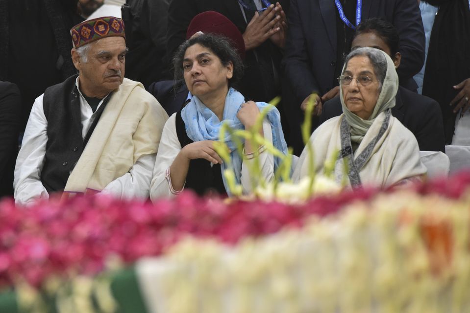 Mr Singh’s wife Gursharan Kaur, right, sits next to his coffin at Congress party headquarters in New Delhi (AP)