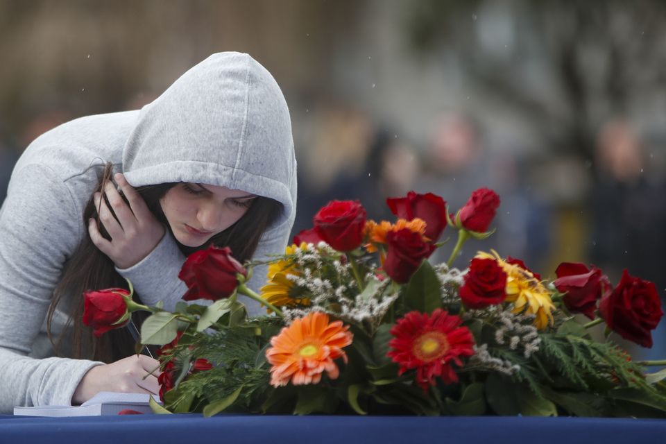 A woman writes a condolence message for the victims of a nightclub fire in the town of Kocani (AP)