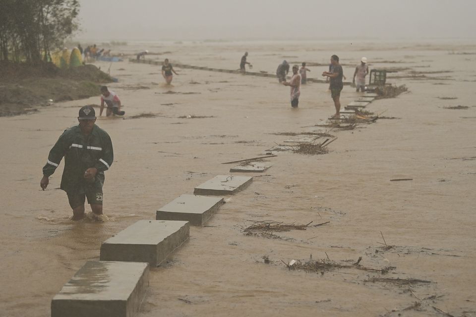 Residents move to safer ground as they evacuate from their homes along a swollen river caused by heavy rains from Typhoon Toraji (Noel Celis/AP)