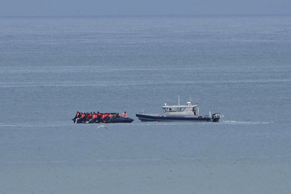 A boat thought to carry migrants is escorted by a vessel from the French Gendarmerie Nationale in the English Channel (Nicolas Garriga/AP)